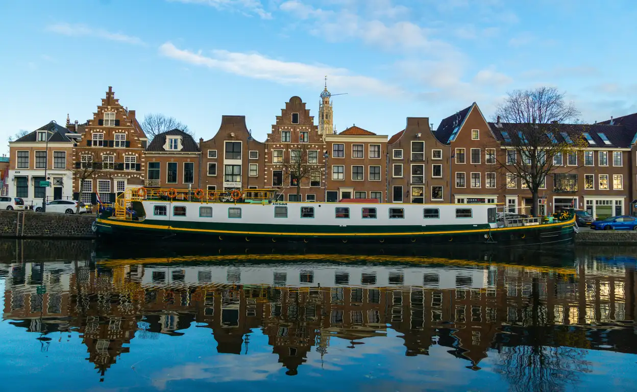 Foto gemaakt vanaf het water. Amsterdamse huizen met een schip aan er voor.
