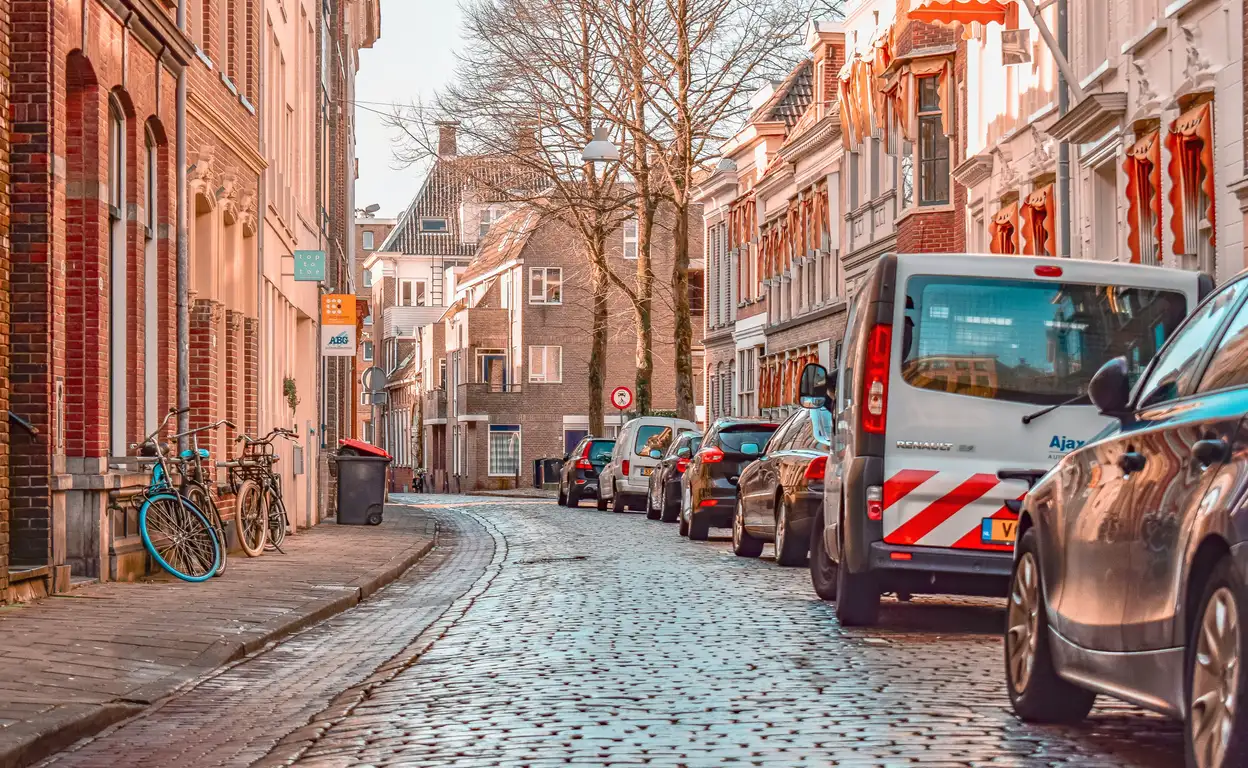 Een mooie straat in Groningen met oude straatstenen en auto's langs de kant.