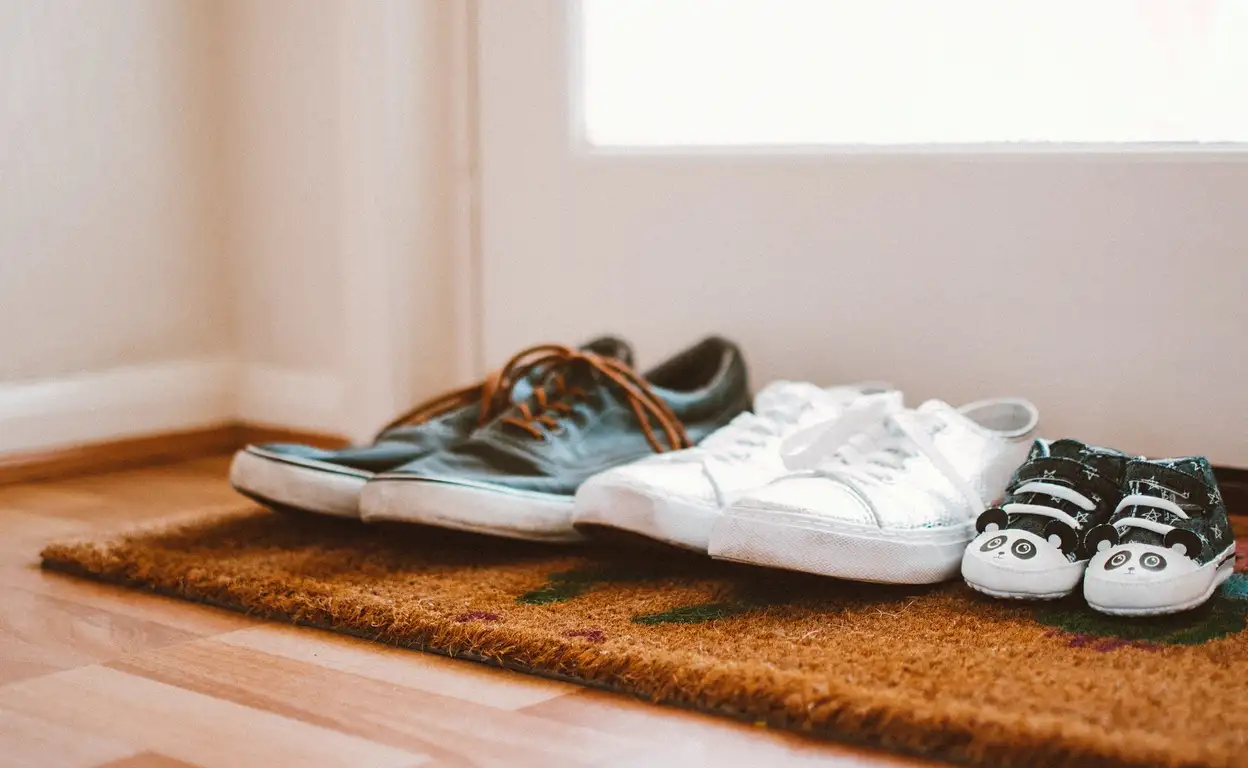 drie paar schoenen op een deurmat