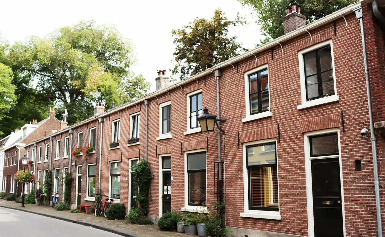 Rij met huurwoningen in Utrecht met bruine stenen en de bomen staan in bloei.