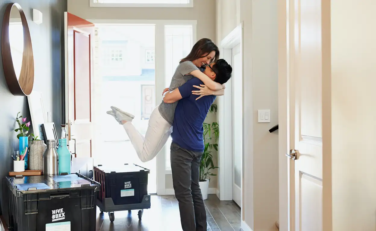 Een man en een vrouw omhelzen elkaar in huis