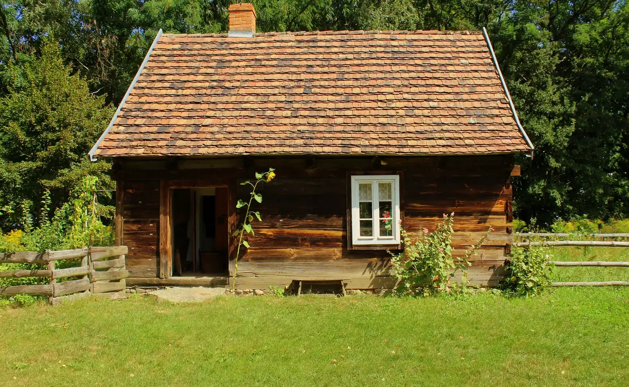 Een houten tiny house op een groot stuk land met gras.