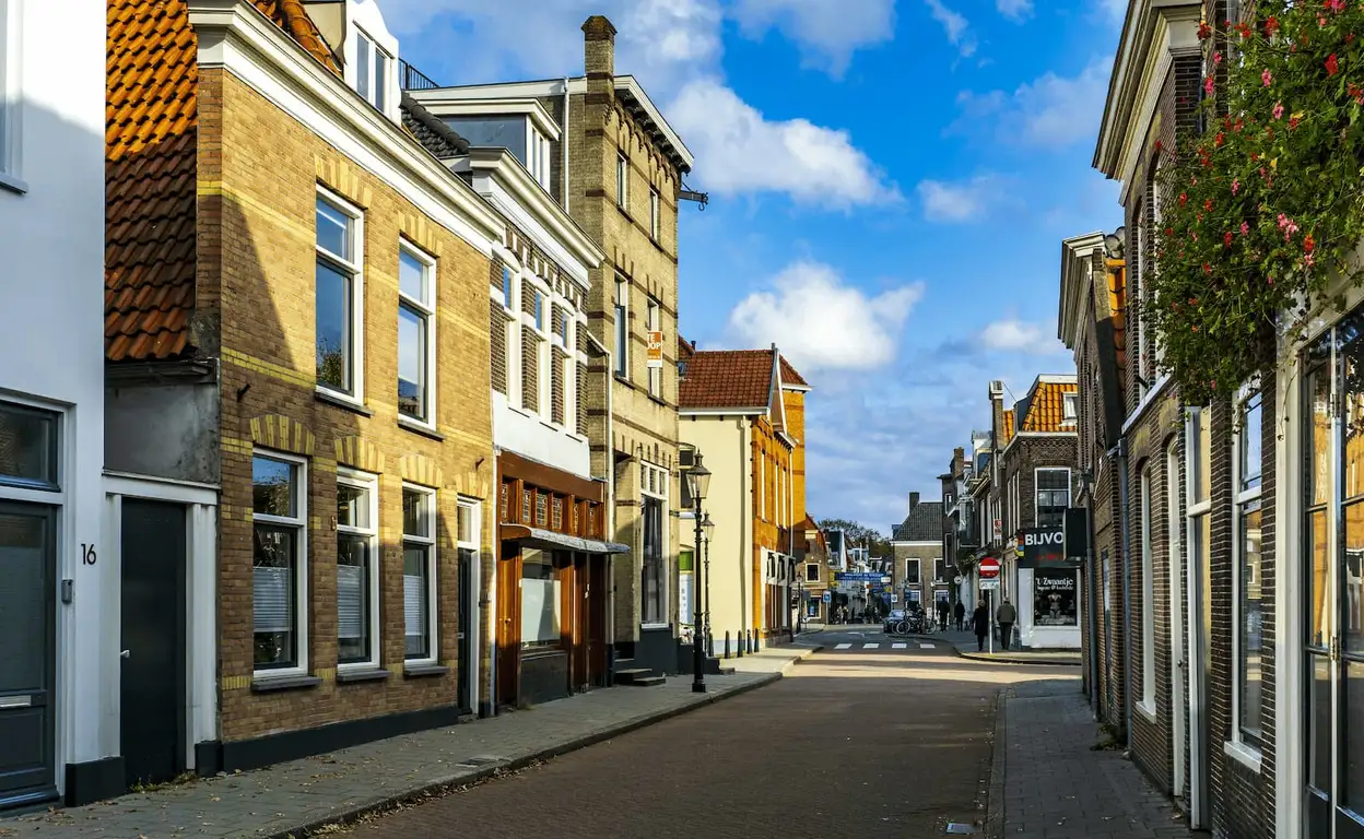 Een Nederlandse straat met huurwoningen en een blauwe lucht