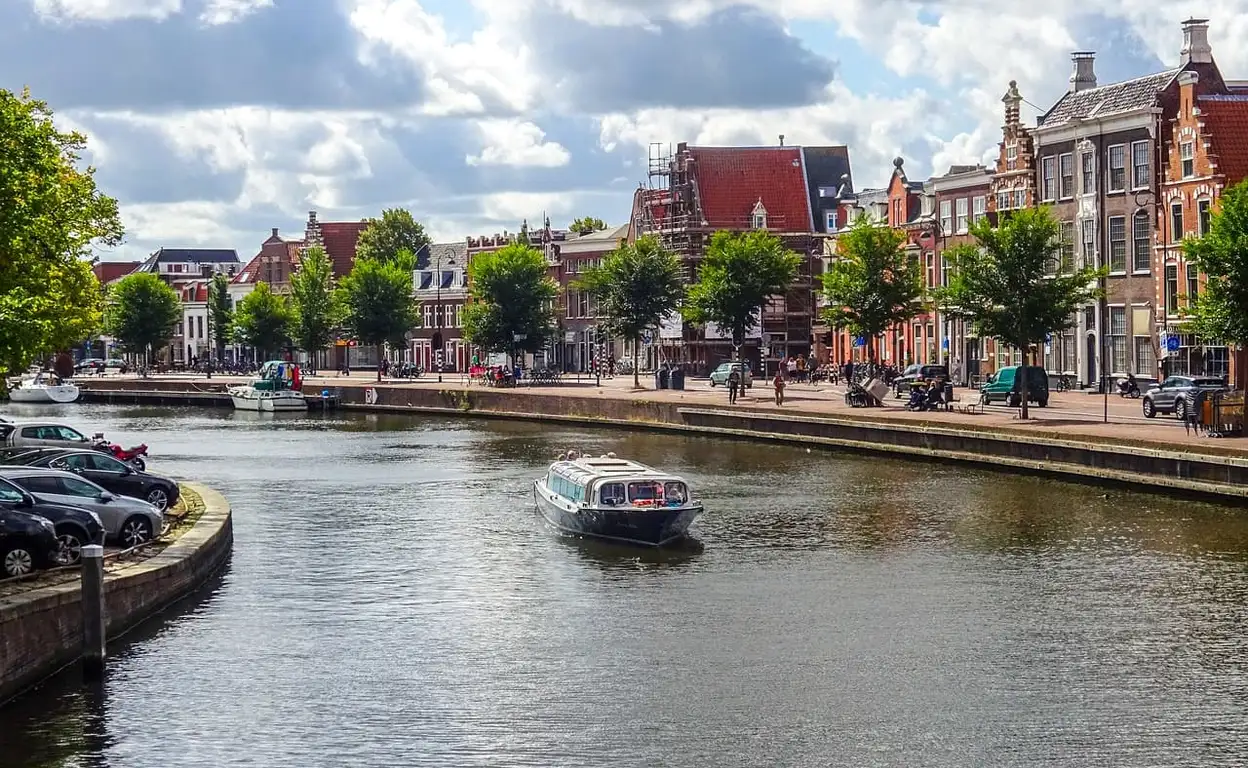 Een kanaal in Haarlem met een rondvaartboot en typisch Nederlandse huizen aan de zijkanten.
