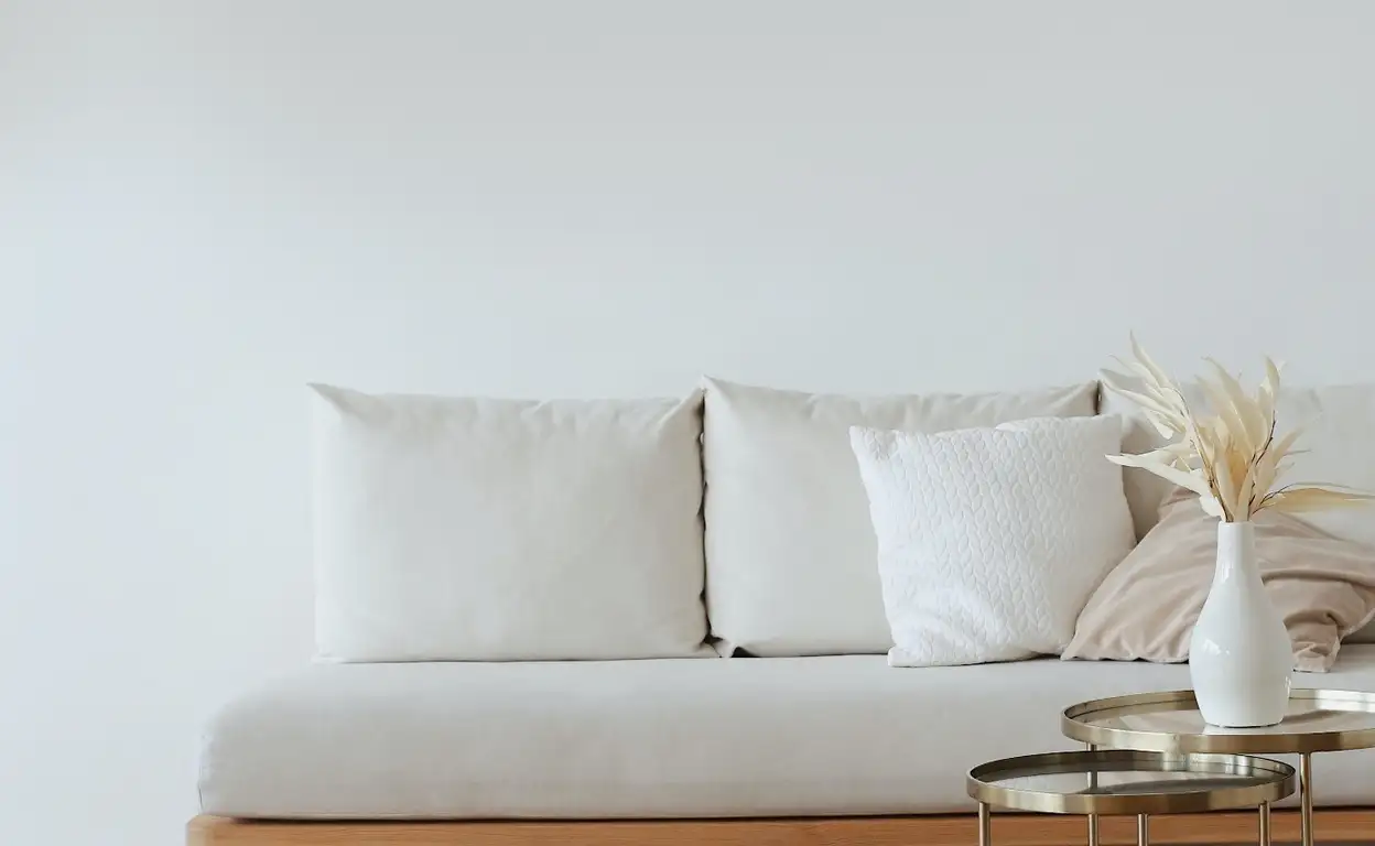 Een opgeruimde woonkamer met een witte bank en veel rotan