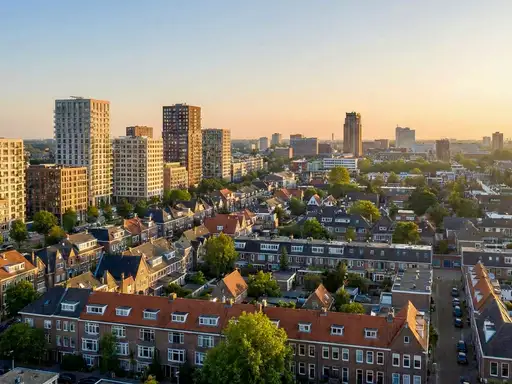 Panoramazicht op een Nederlandse stad bij zonsopgang, met een combinatie van traditionele laag en hoogbouw.