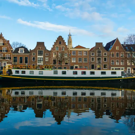 Foto gemaakt vanaf het water. Amsterdamse huizen met een schip aan er voor.