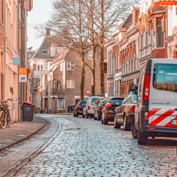 Een mooie straat in Groningen met oude straatstenen en auto's langs de kant.