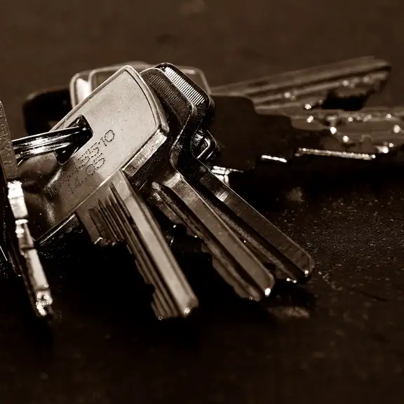 Een sleutelbos met grijze huissleutels tegen een donkere achtergrond.