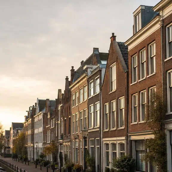 Nederlandse grachtenpanden met een subtiel ‘Te huur’-bord in een raam.