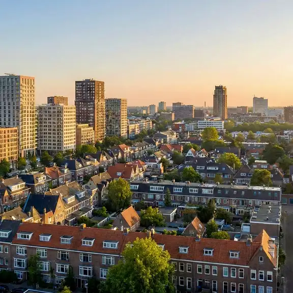 Panoramazicht op een Nederlandse stad bij zonsopgang, met een combinatie van traditionele laag en hoogbouw.