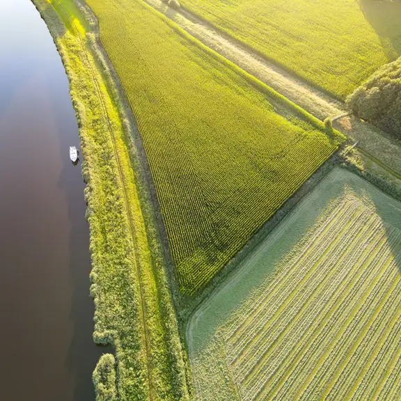 Een foto van bovenaf van weilanden en waterwegen