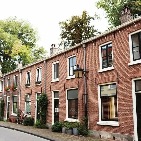 Rij met huurwoningen in Utrecht met bruine stenen en de bomen staan in bloei.