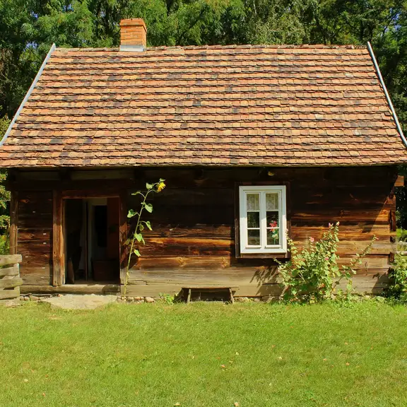 Een houten tiny house op een groot stuk land met gras.