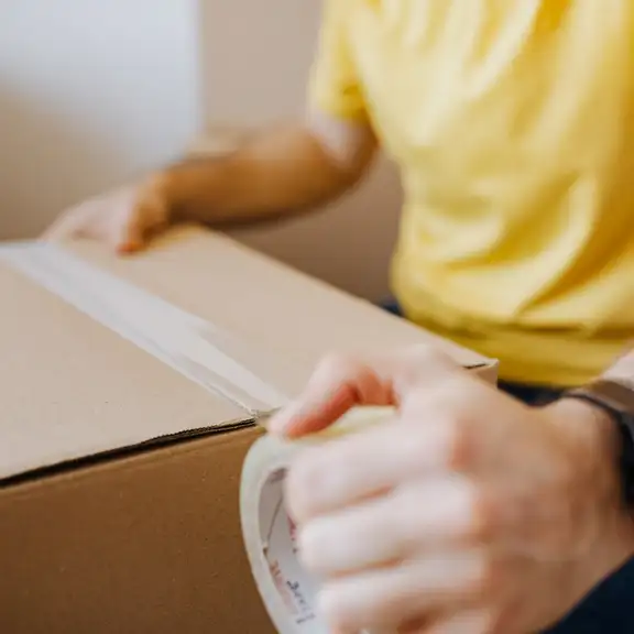 Een man taped een verhuisdoos dicht