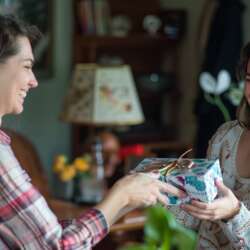 Een vrouw overhandigt een housewarming cadeau aan een andere vrouw