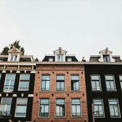 Rij met typische Nederlandse huizen in Amsterdam, de focus ligt op de ramen