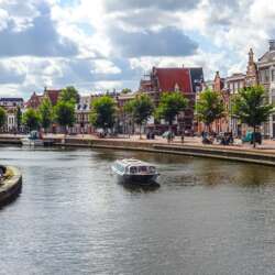 Een kanaal in Haarlem met een rondvaartboot en typisch Nederlandse huizen aan de zijkanten.