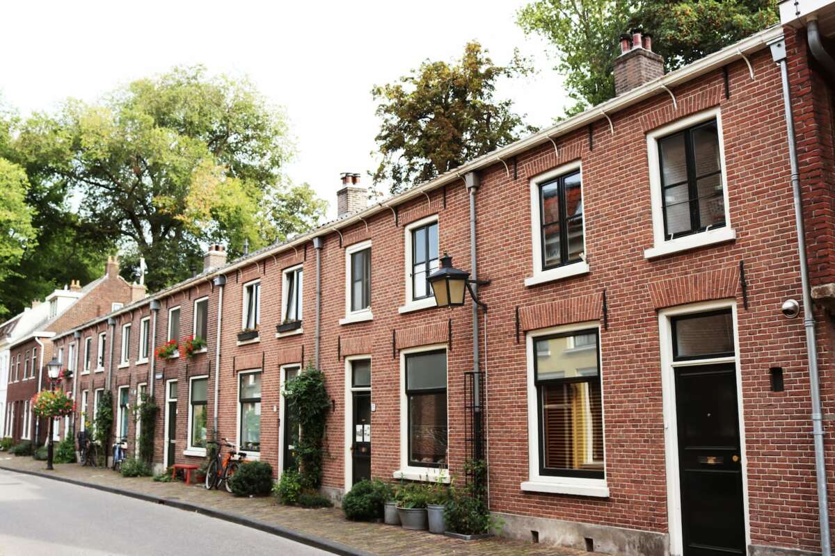 Rij met huurwoningen in Utrecht met bruine stenen en de bomen staan in bloei.
