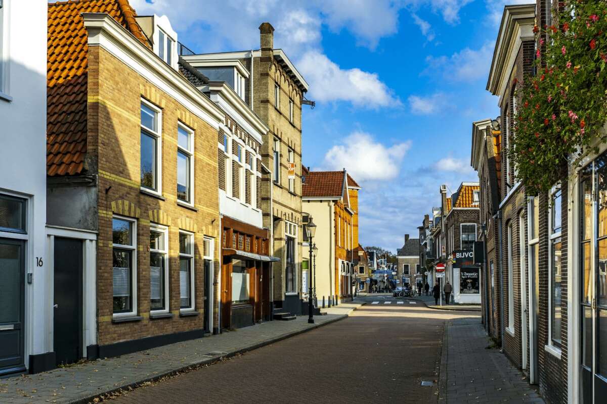 Een Nederlandse straat met huurwoningen en een blauwe lucht